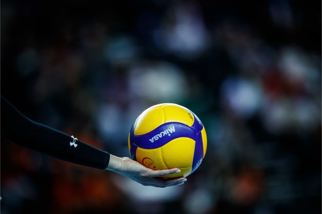 Jogador de voleibol com bola na quadra de vôlei